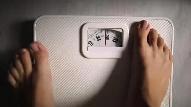 standing on scales to measure weight loss